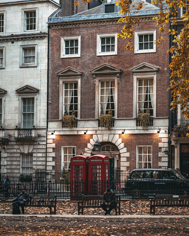 Georgian townhouses and two red telephone boxes on Berkeley Square in autumn