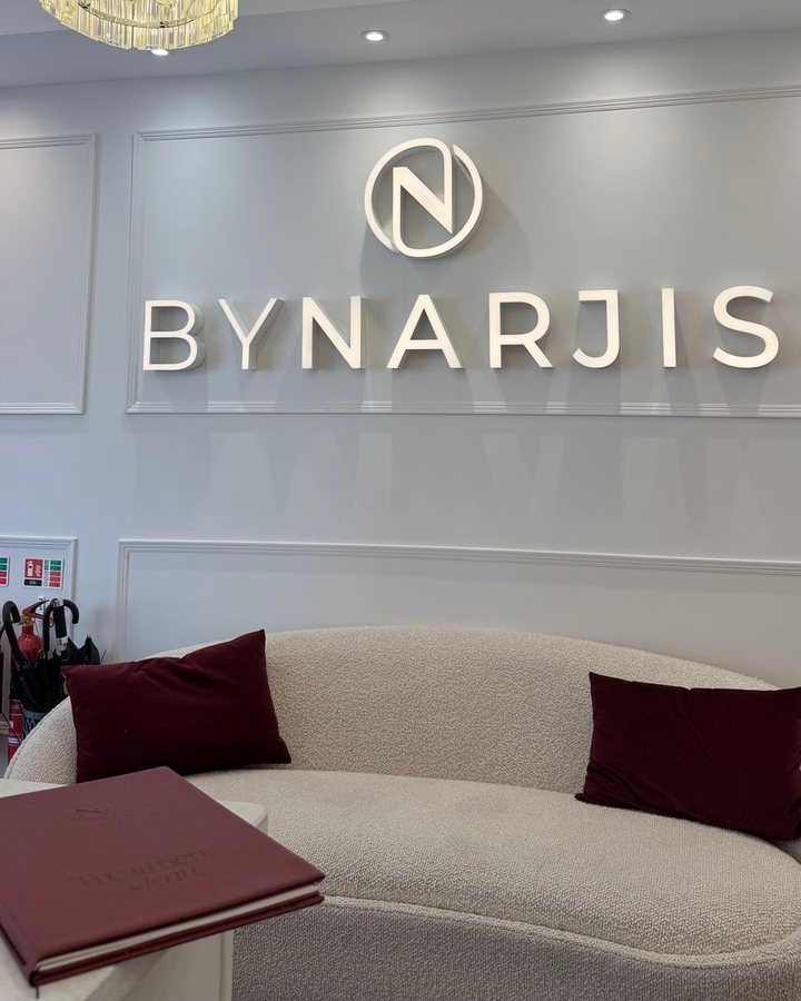 The lounge at By Narjis: a boucle sofa under the lit logo and a chandelier