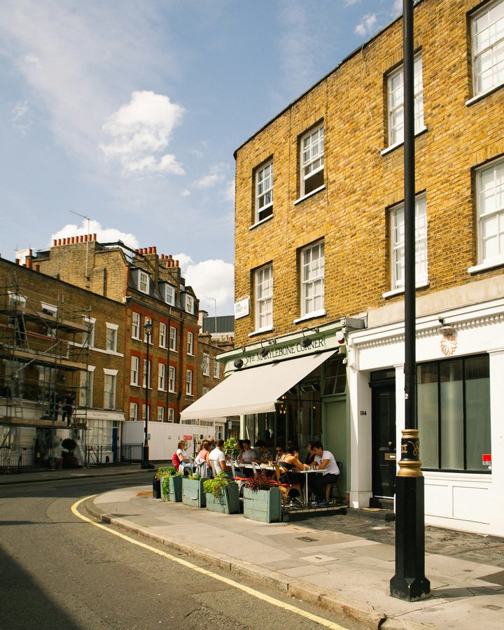 A street corner in Marylebone: yellow brick houses and a cafe awning in the sun