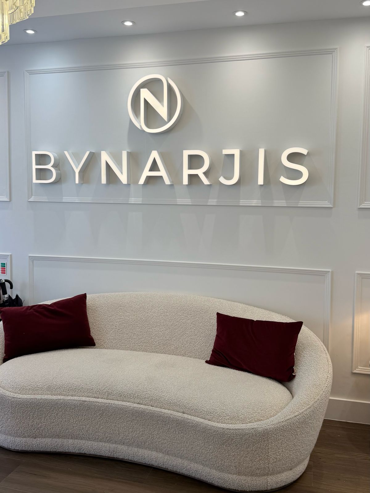 Reception at By Narjis: the clinic’s name on the wall above a curved sofa