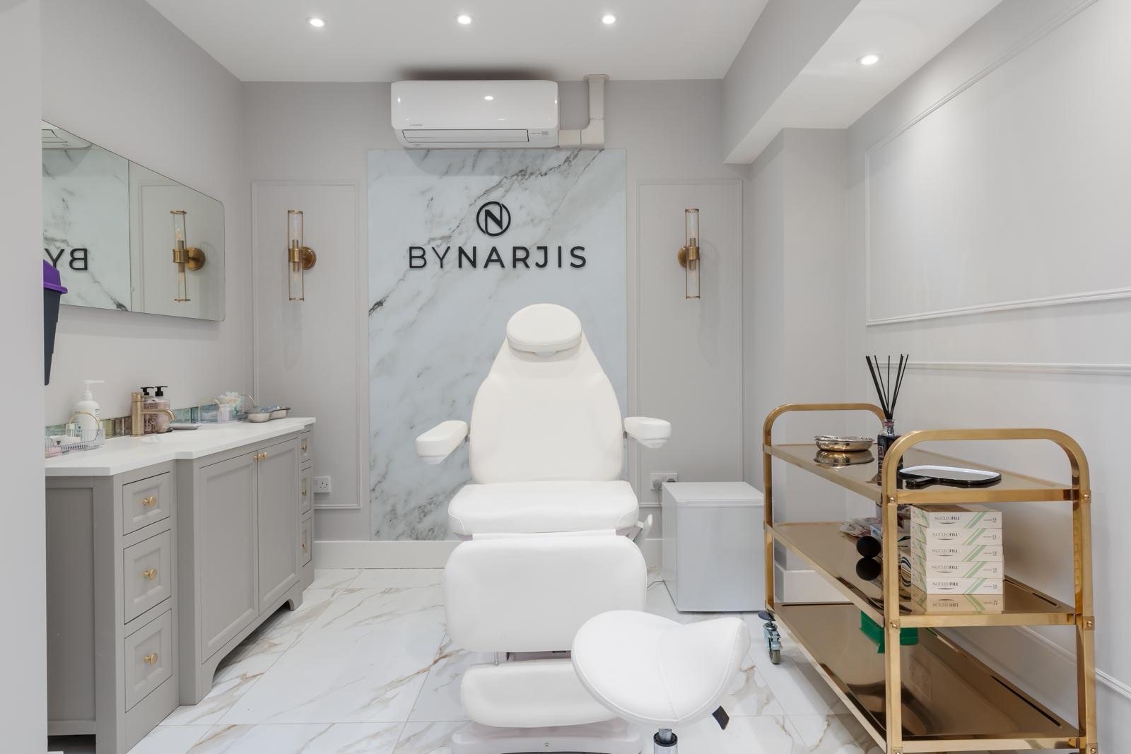 The treatment room at By Narjis: the treatment chair before a marble wall with the clinic’s name