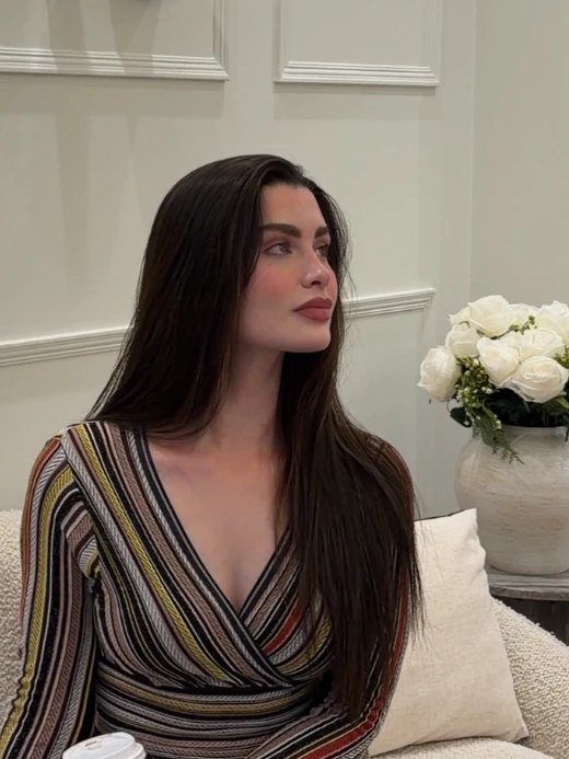 Rawan seated in the clinic’s waiting room, looking to one side, white roses behind her